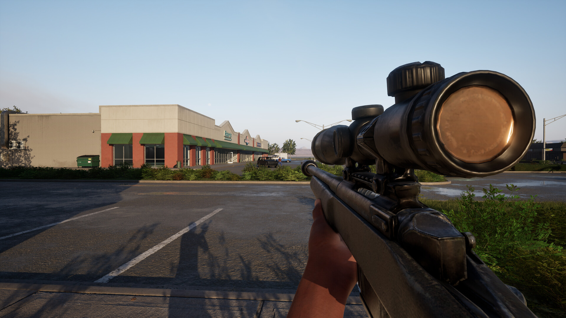 A scoped rifle overlooking a wide shopping-plaza parking lot and distant storefronts
